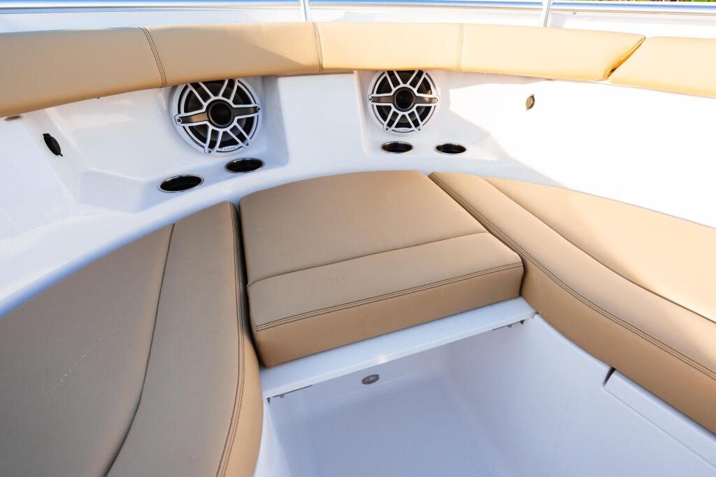 Tan leather seating and white hardtop interior with dual speakers and storage compartment in boat cabin