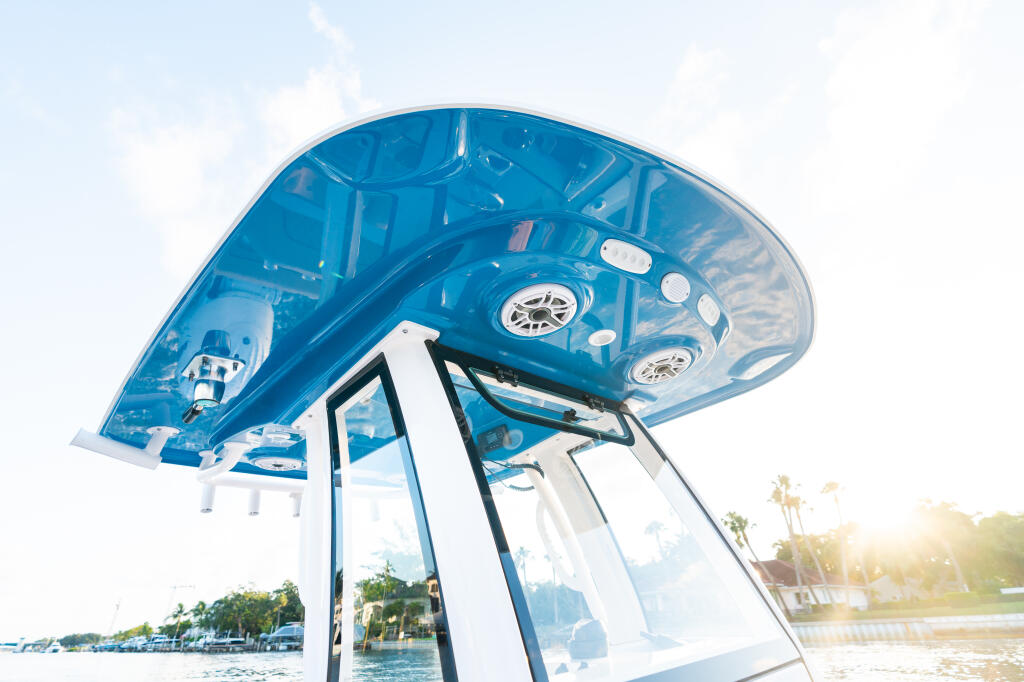 Blue fiberglass hard-top with built-in lighting and integrated controls viewed from below at a marina