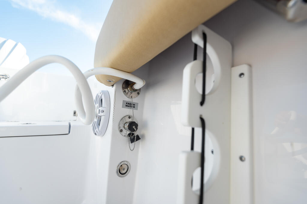 Freshwater washdown system with white mounting bracket and control valve on boat hull