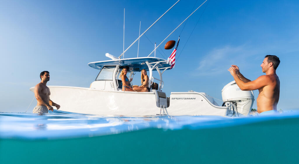 Couple swimming and enjoying a boat day in clear turquoise waters with others relaxing aboard