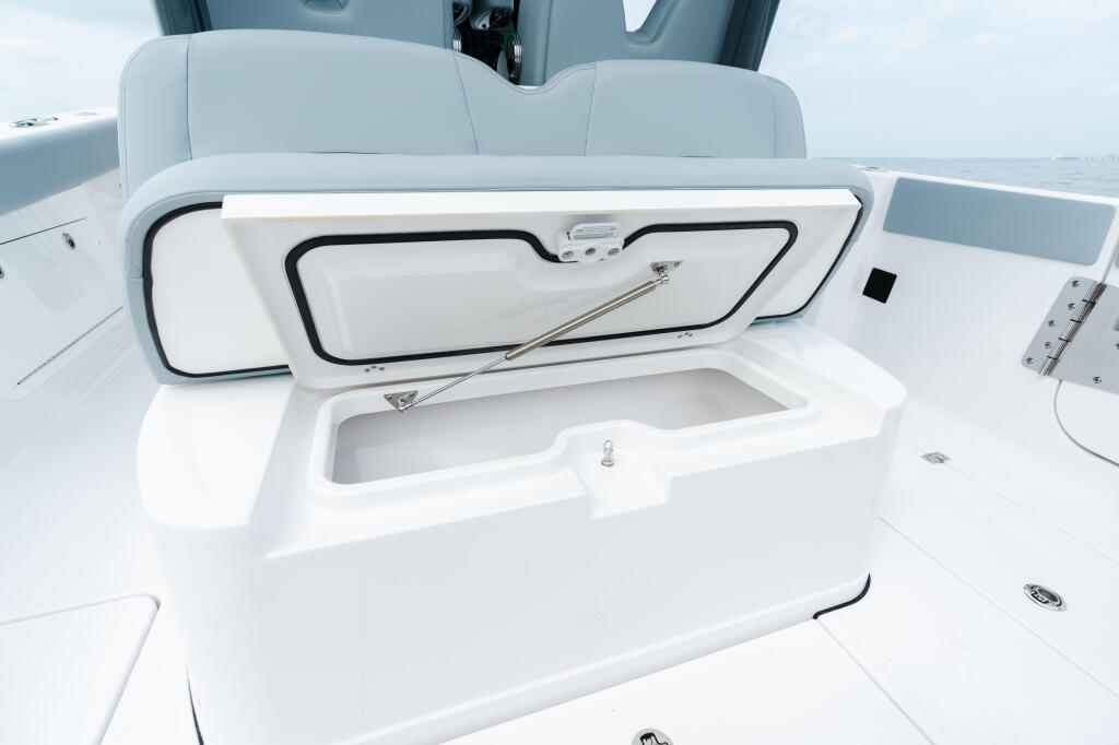 Open white storage locker with gas strut lid and stainless steel handle on boat deck
