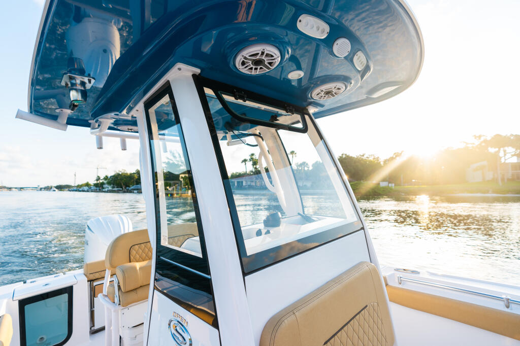 Center console boat with integrated tempered glass windshield and manual vent at marina during golden hour