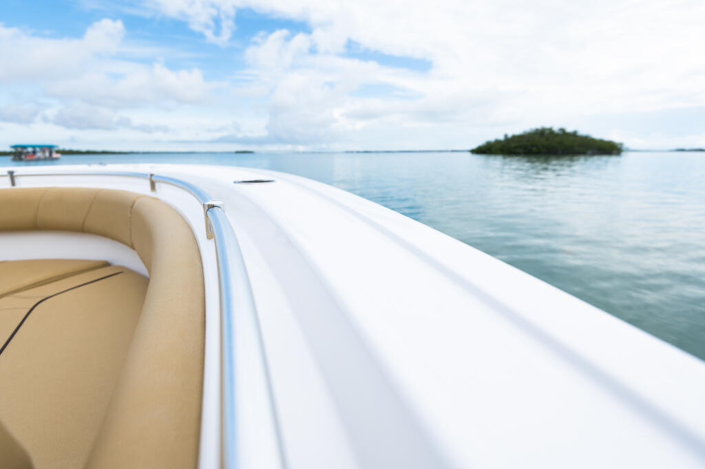 Tan upholstered seating along the gunwale of a center console boat in calm tropical waters