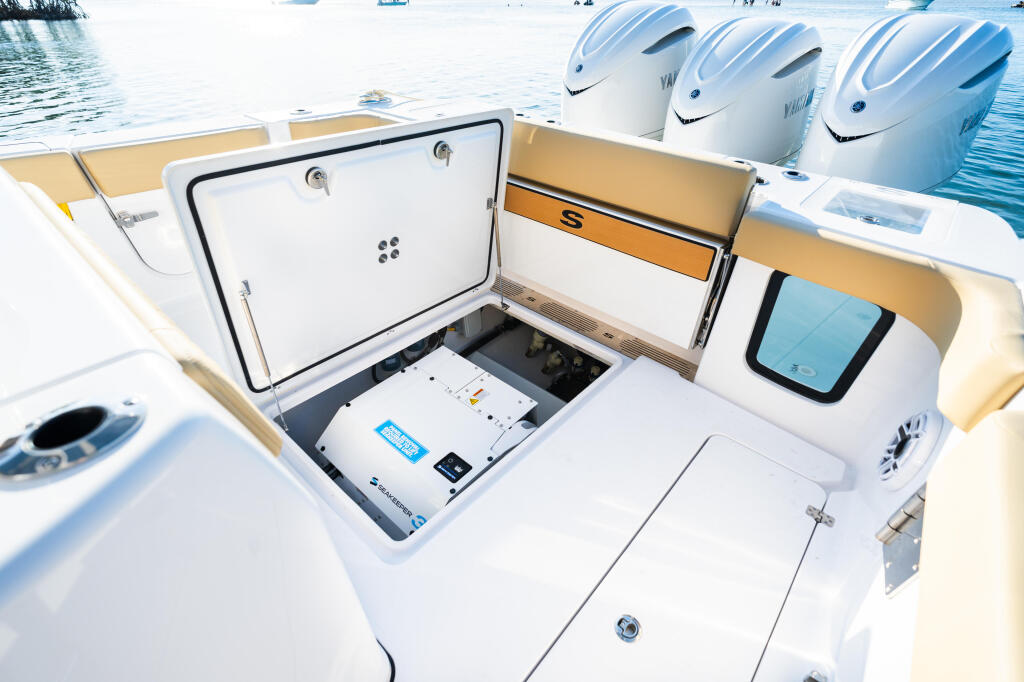 Open helm console with electronics, storage compartments, and three white outboard engines visible in background