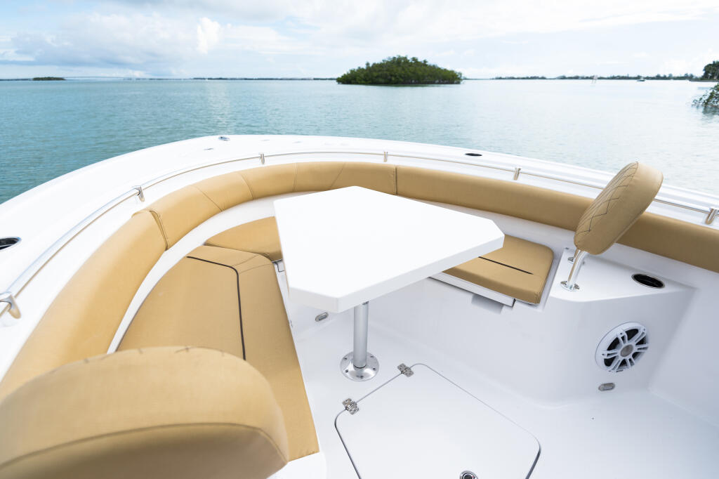 Spacious bow seating area with tan cushioned seating, removable table, and calm tropical waters with mangrove island beyond