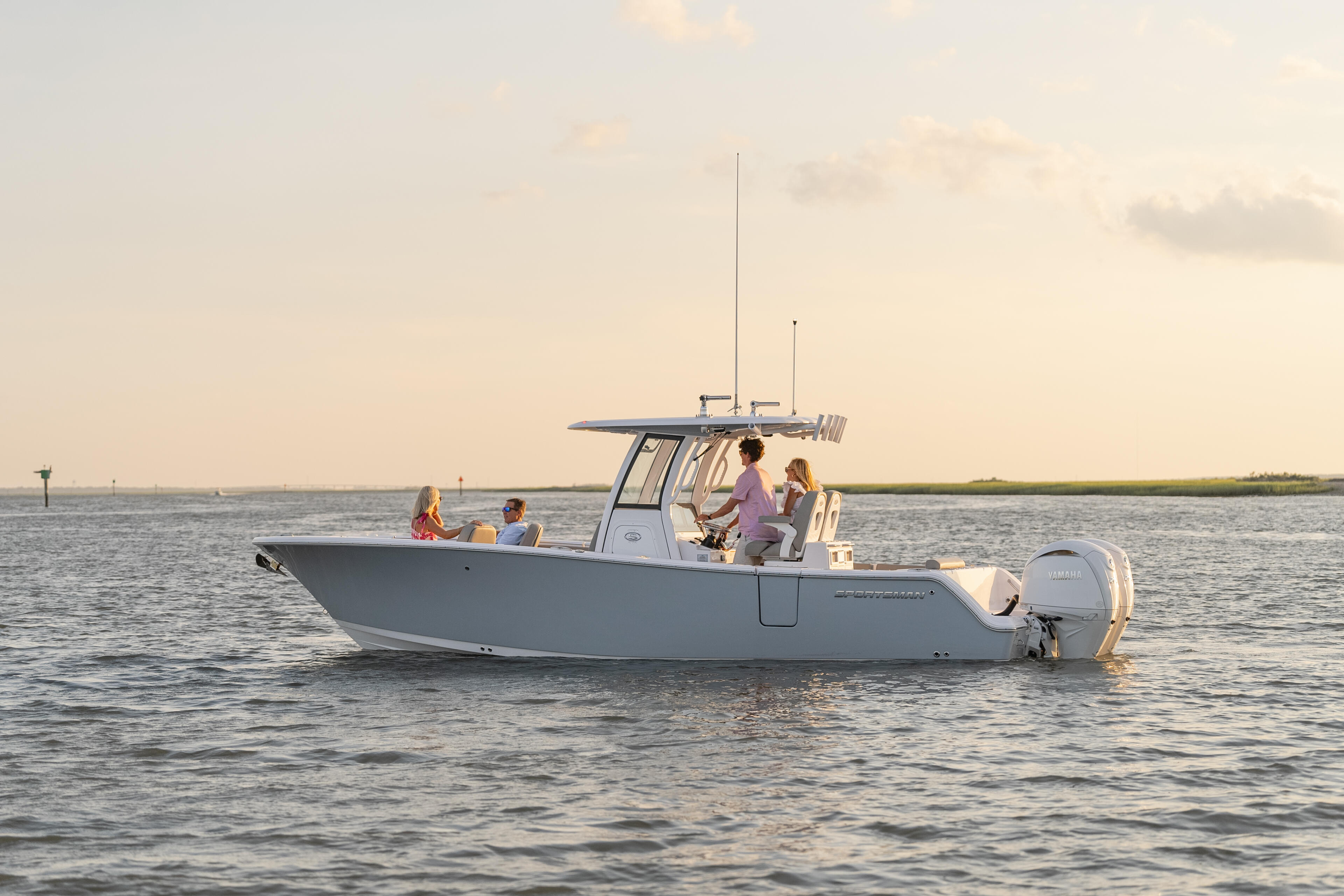 Family of four enjoying a boat cruise at sunset with calm coastal waters in background
