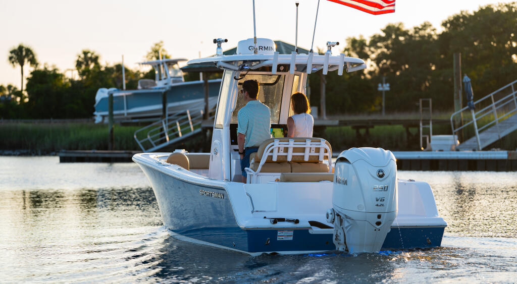 Couple boarding a white center console boat at a marina with American flag and Garmin electronics