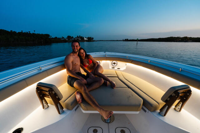 Couple relaxing on illuminated seating in the bow of a boat at dusk