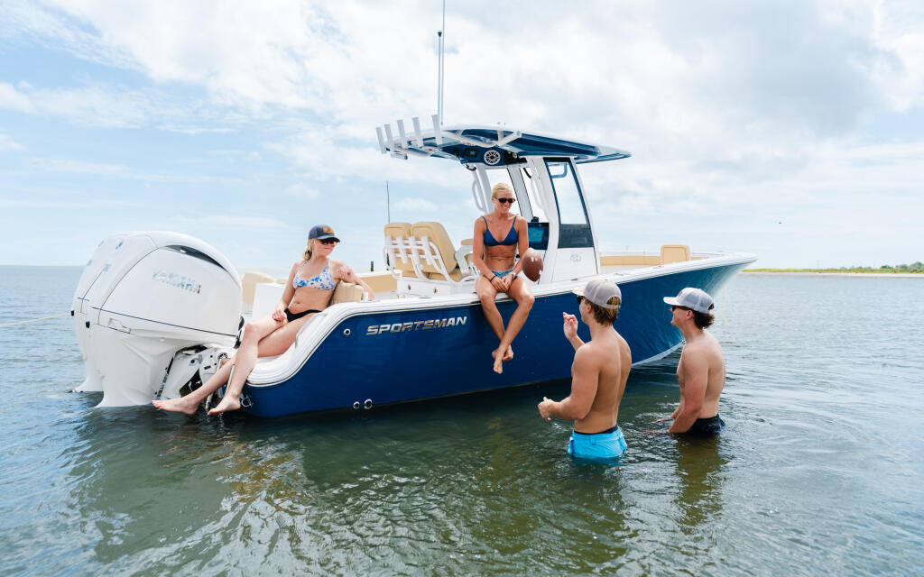 Group enjoying swimming and socializing at a sandbar from a blue and white Sportsman center console boat