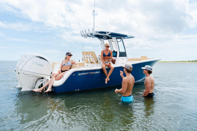 Group enjoying swimming and socializing at a sandbar from a blue and white Sportsman center console boat