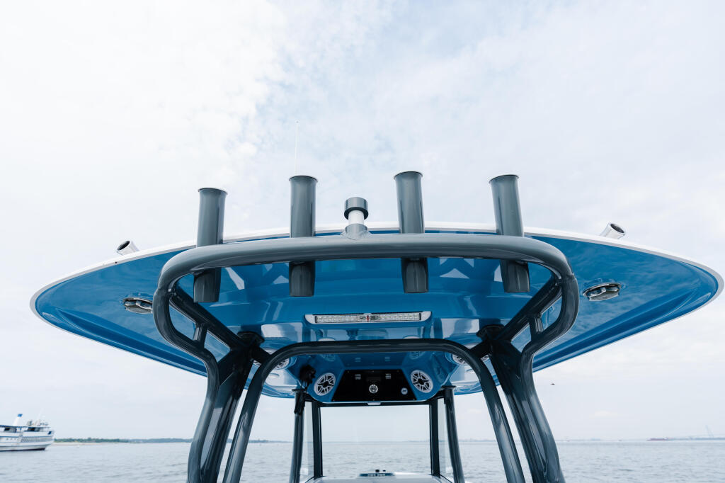 Hard-top helm station with blue canopy, dual gauge clusters, and windshield viewed from above on calm water