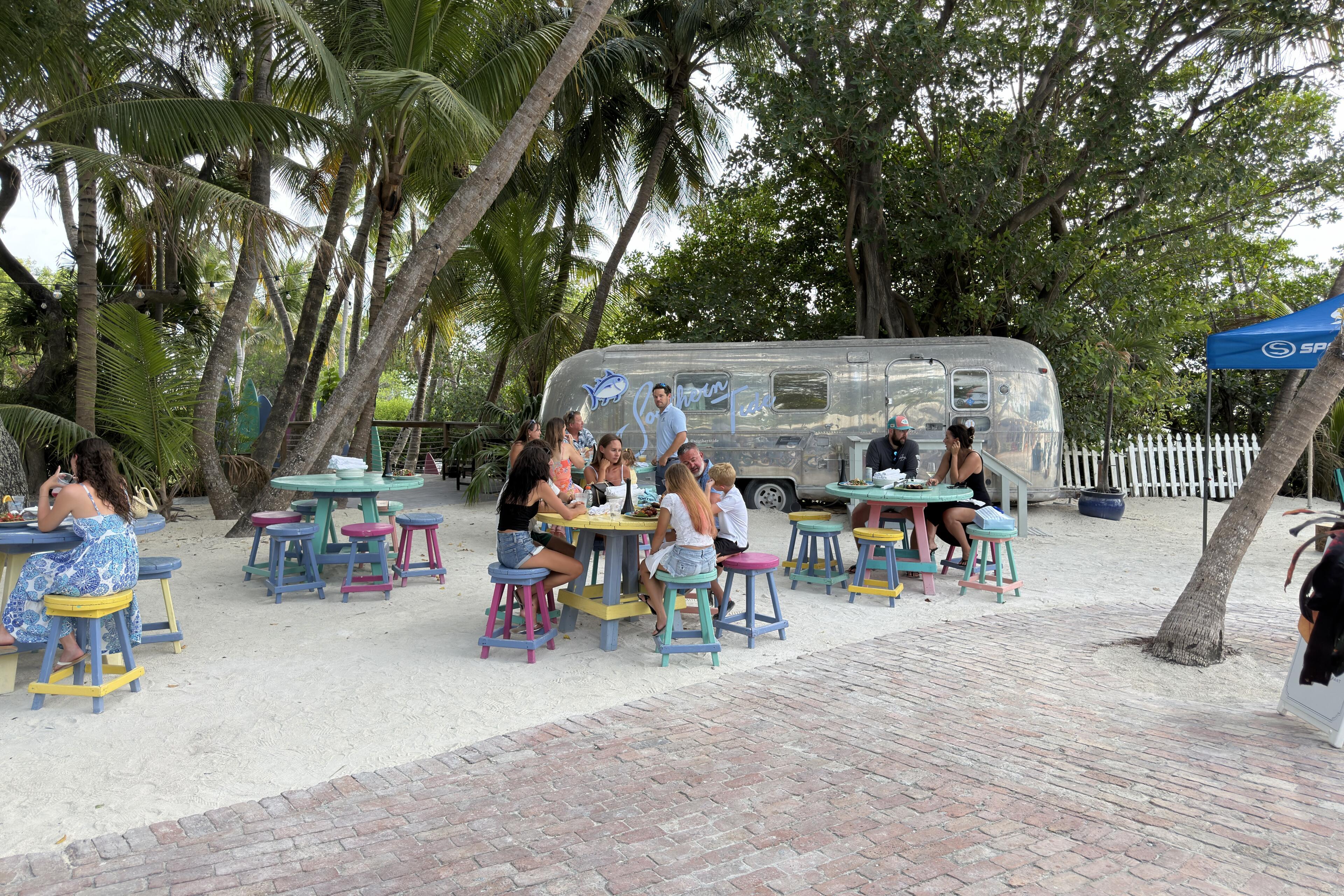 Family gathering at a beachside airstream trailer with colorful seating and palm trees