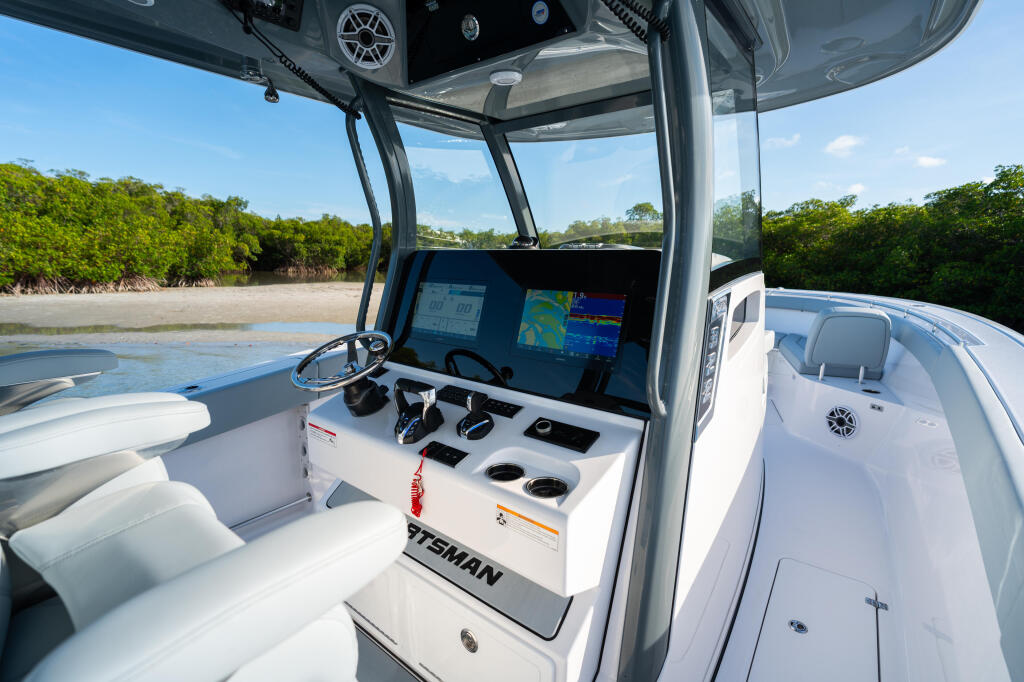 Helm station with dual monitors and controls overlooking shallow mangrove waters and sandy shoreline