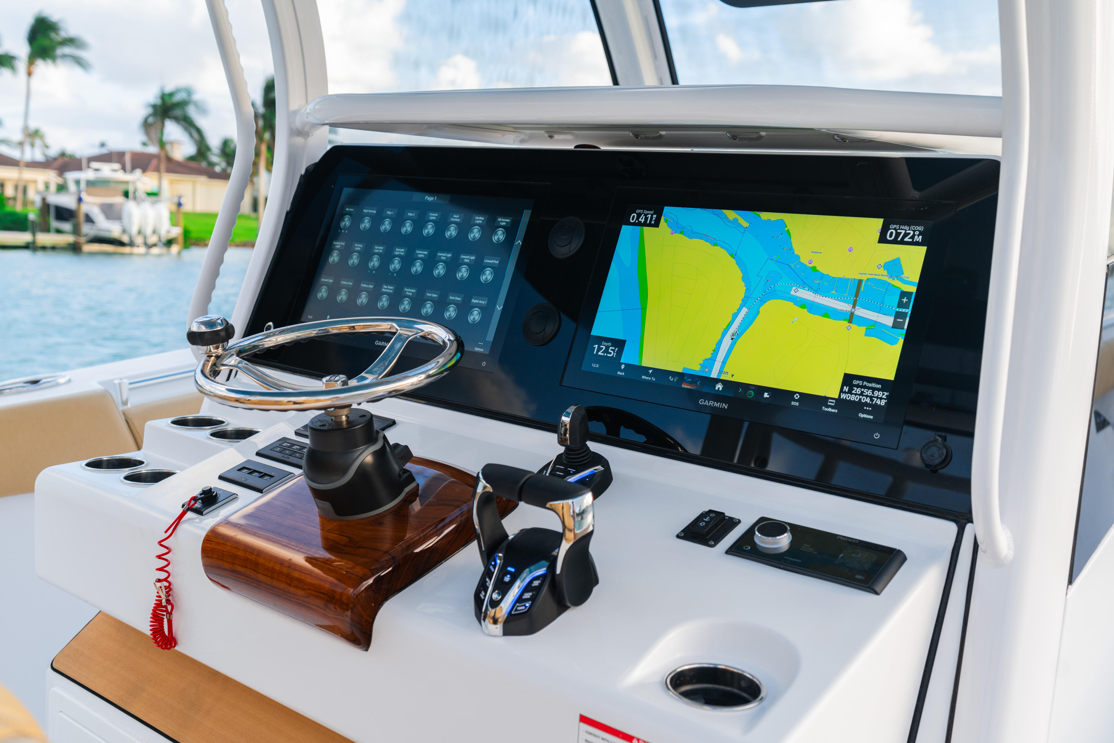 Helm station with twin monitor displays showing GPS navigation and weather data, steering wheel, and control systems