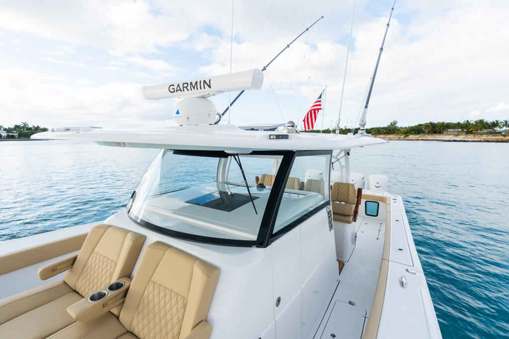 White fishing boat with Garmin radar antenna docked at marina with calm blue water and palm trees