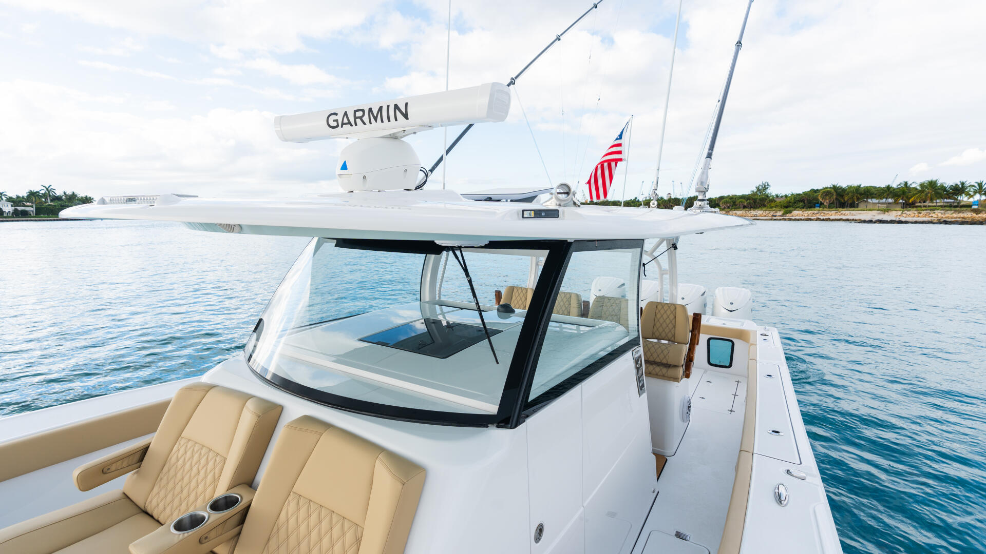 White fishing boat with Garmin radar antenna docked at marina with calm blue water and palm trees