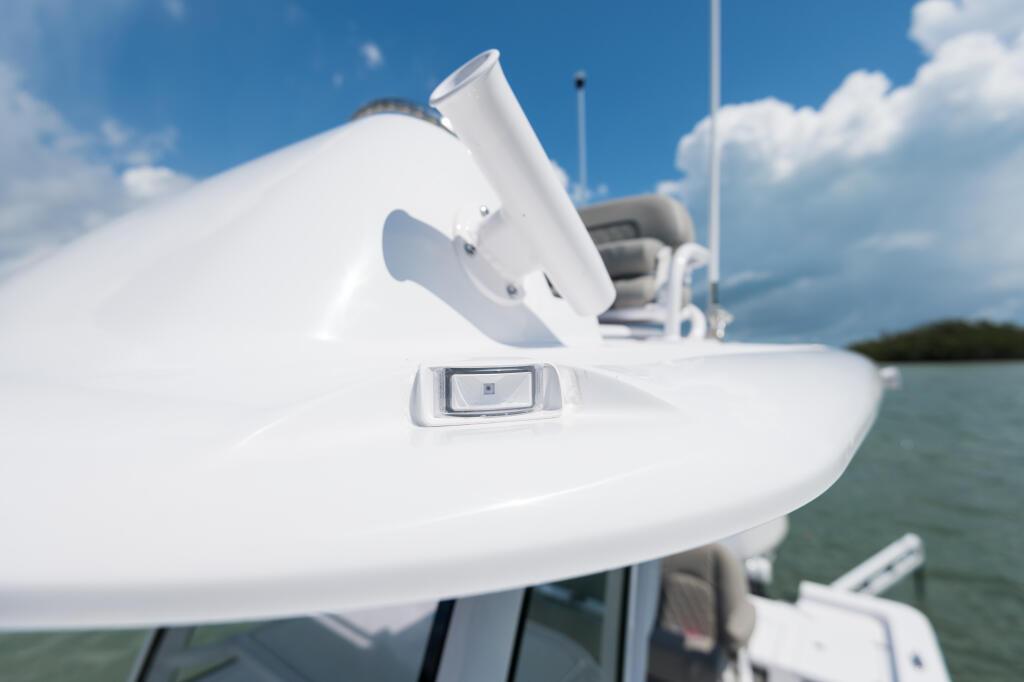 Molded navigation light mounted on the curved white hard-top structure of a bay boat