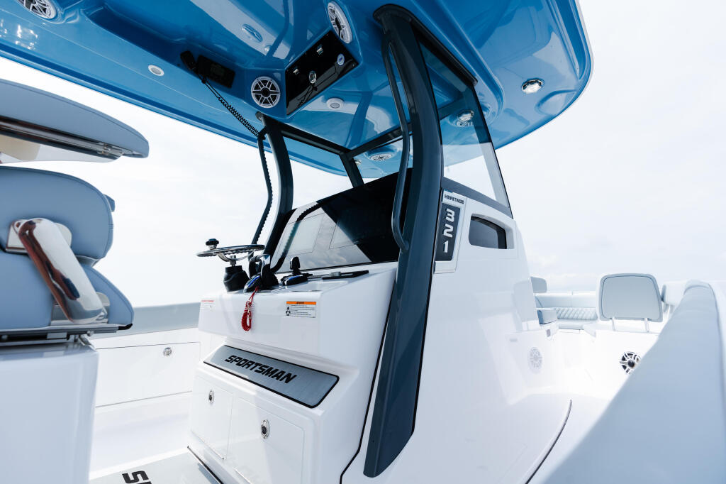 Open helm door of blue and white Sportsman boat with steering wheel and controls visible