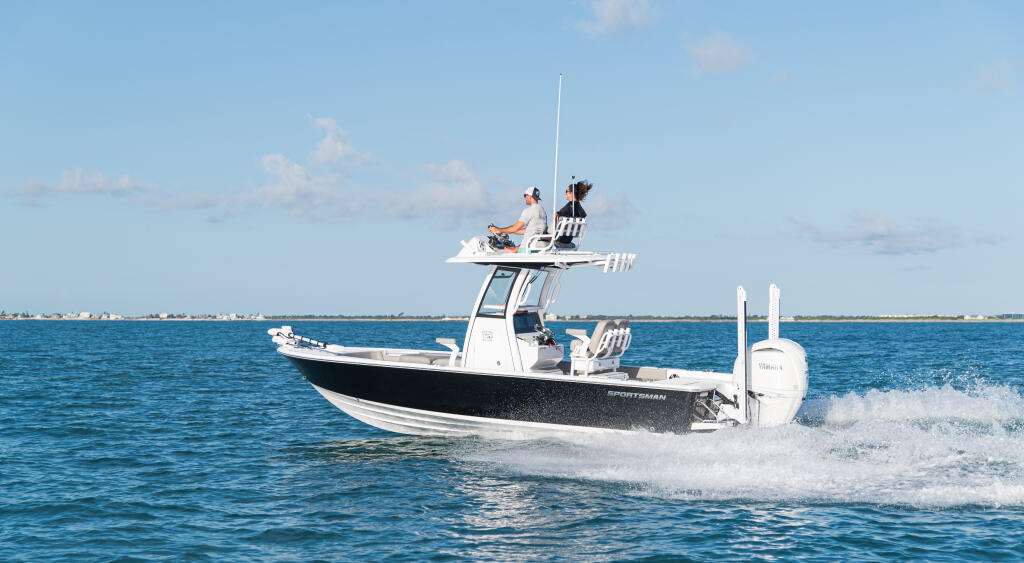 Sportsman bay boat running offshore with two people on the elevated platform in calm blue water