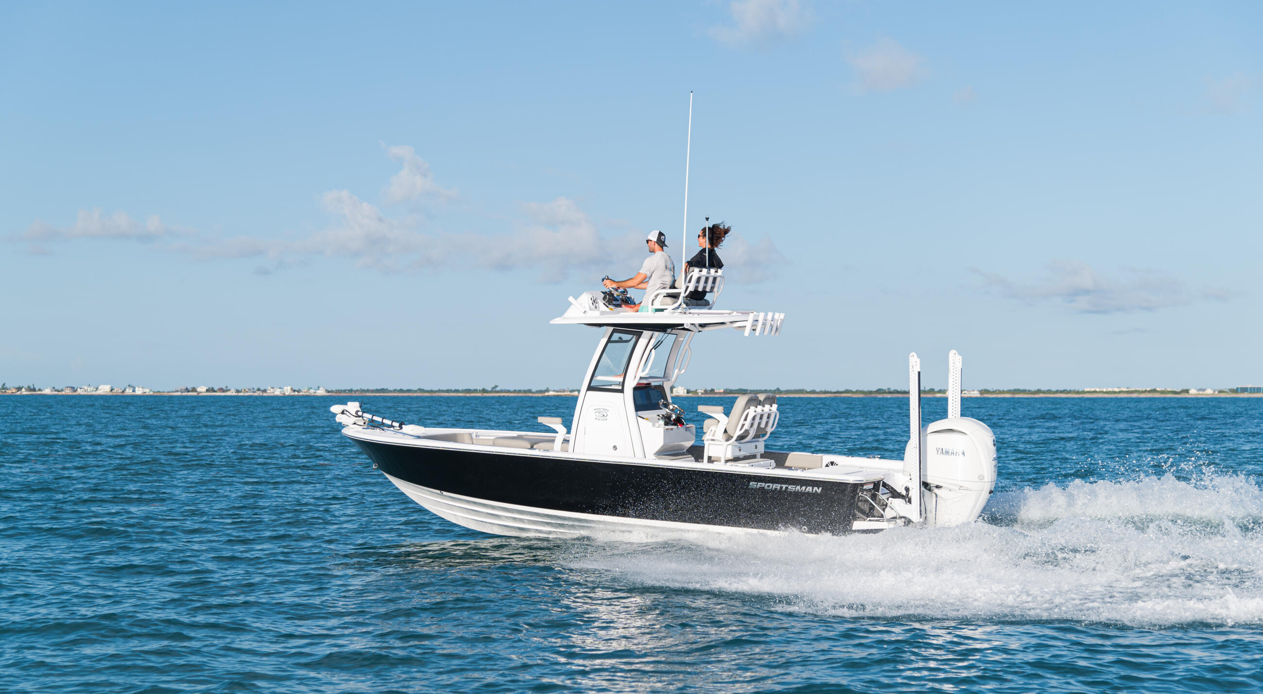 Sportsman bay boat running offshore with two people on the elevated platform in calm blue water