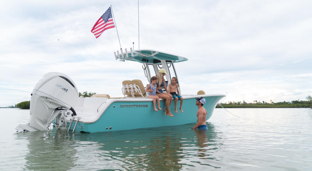 Family enjoying a turquoise center console boat anchored in shallow sandbar waters with an American flag flying