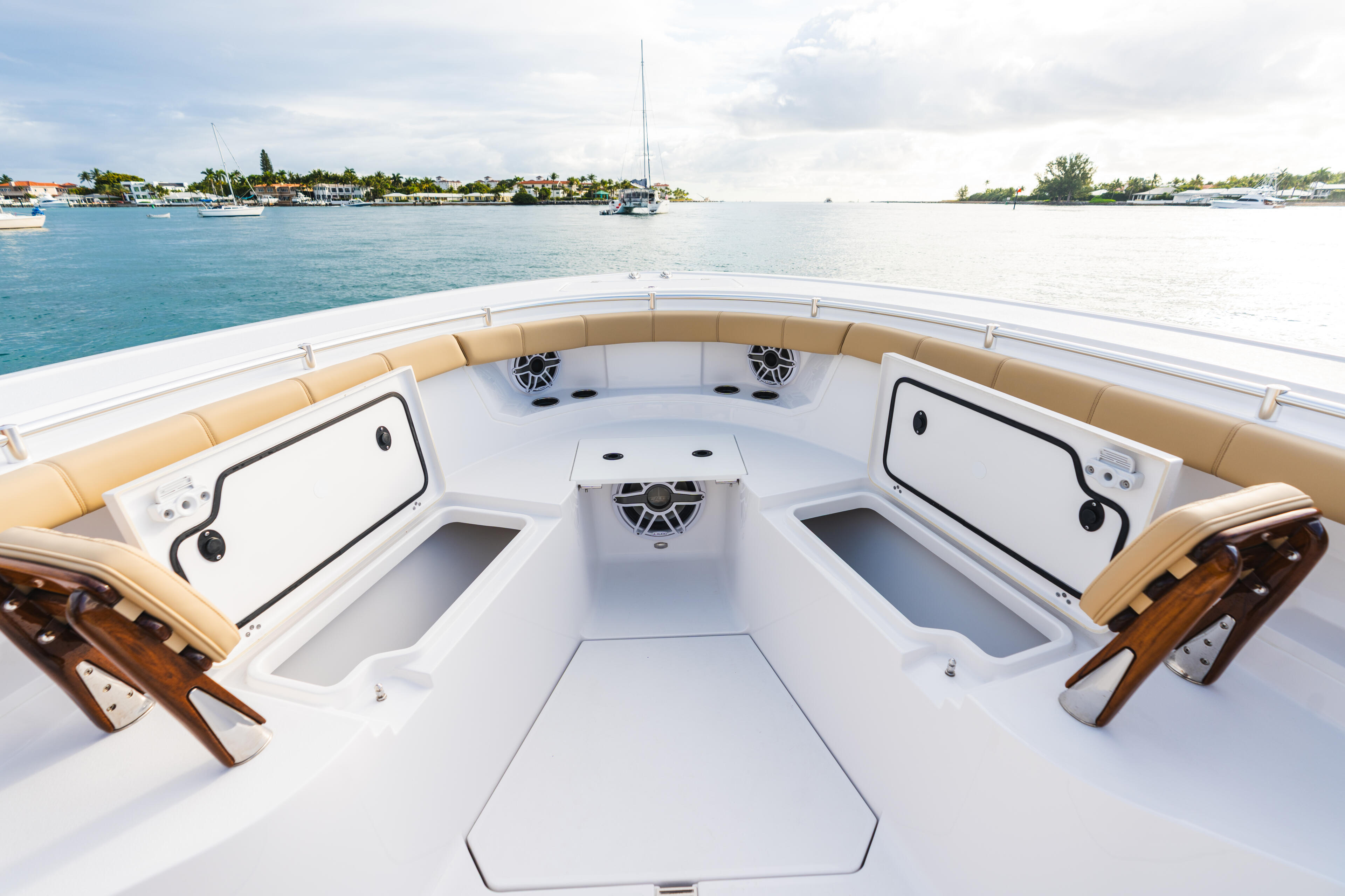 Spacious bow seating area with tan cushions and storage compartments overlooking calm turquoise marina water