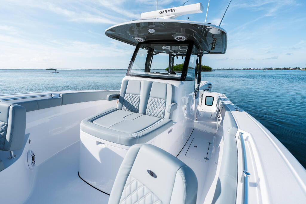 Open boat with white quilted seating, hard-top canopy, and Garmin electronics on calm blue water