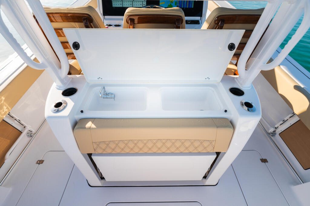 Open transom with white fiberglass, tan upholstered bench seat, and storage compartments viewed from above