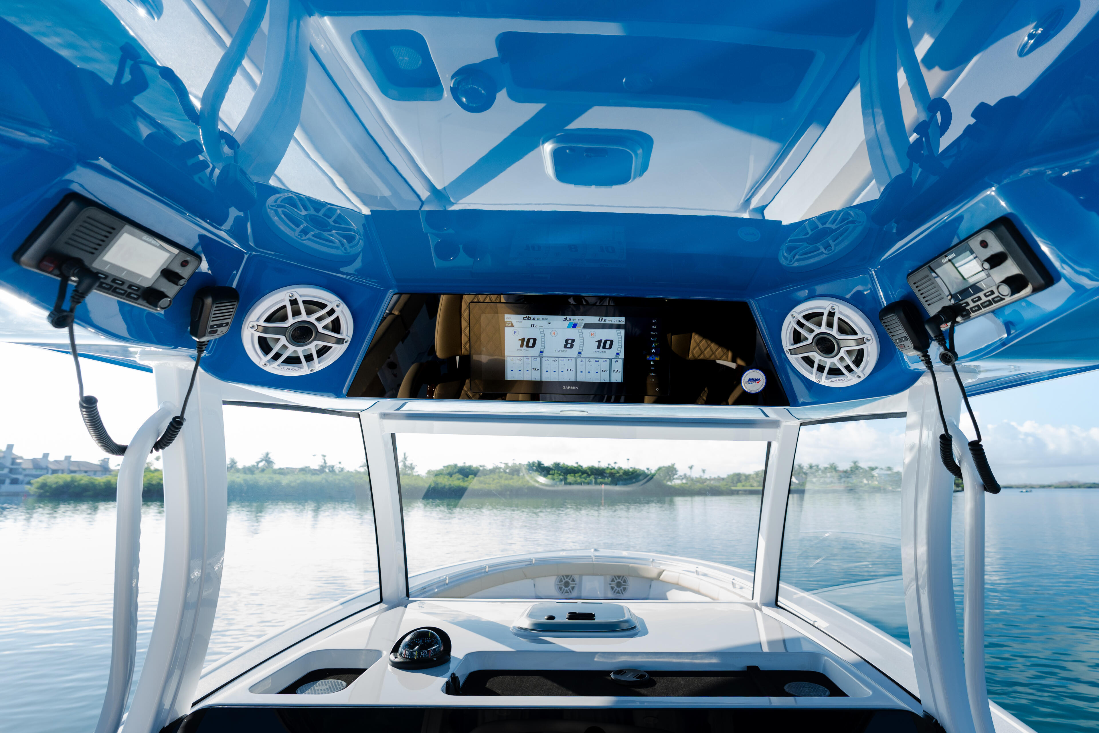 Interior view of boat cabin with hard-top, dual speakers, digital display, and scenic water views ahead