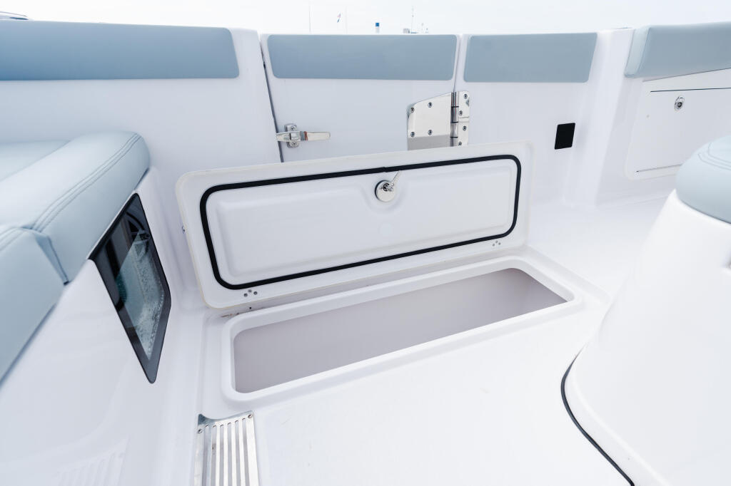 Open livewell storage compartment with gray cushioned seating visible in bright cabin interior