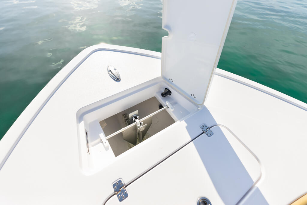 Open bow anchor locker with integrated storage on a white center console boat with clear turquoise water visible