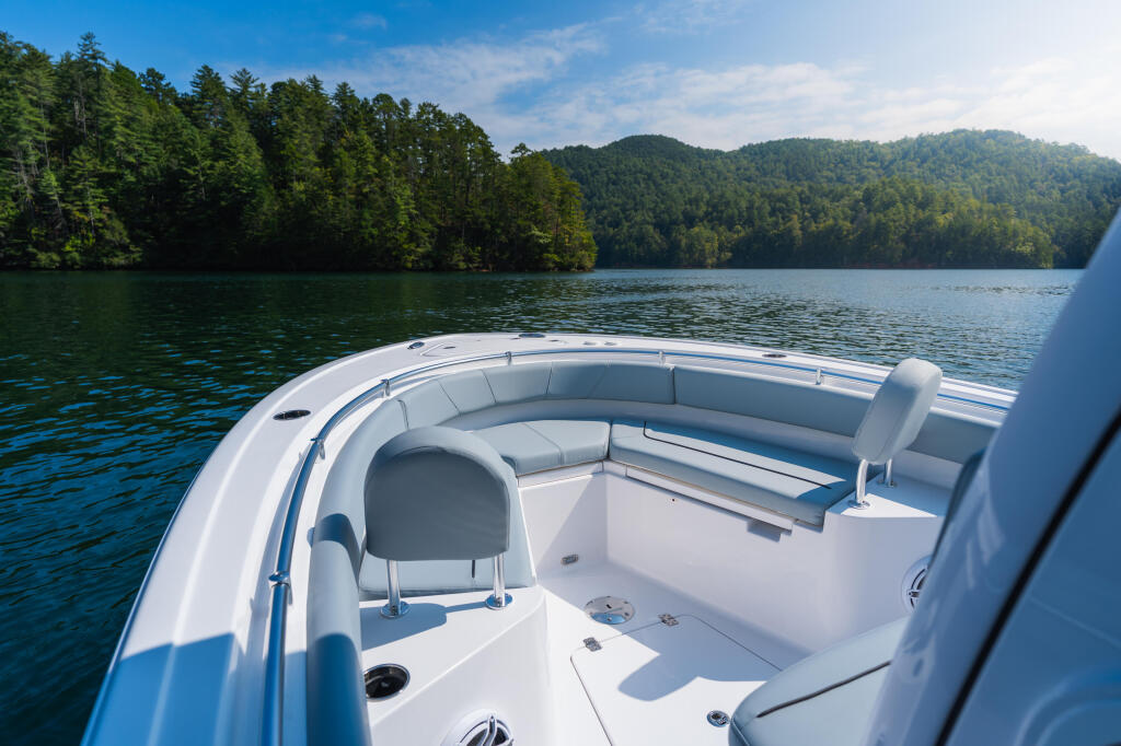 Bow seating and console layout on a center console boat with forested lake shoreline in background