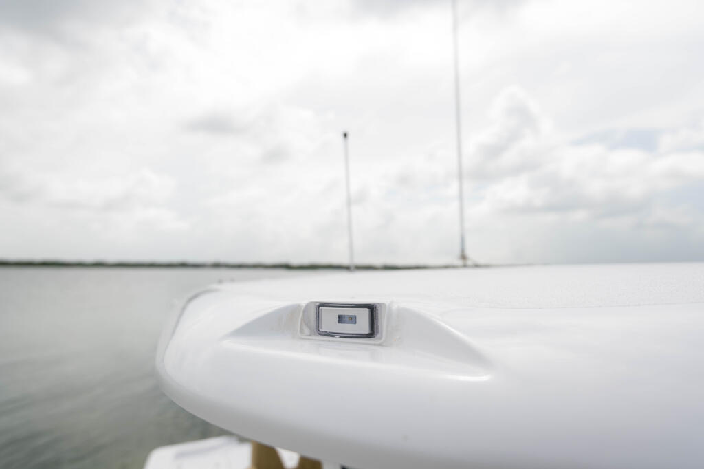 Molded-in navigation light detail on boat's hard-top with calm water and sailboats in background