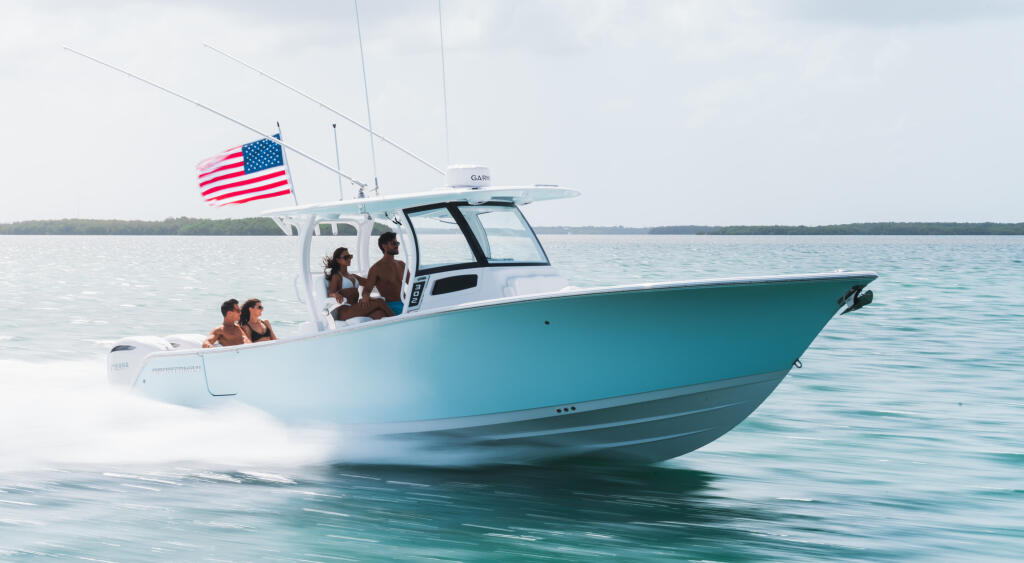Turquoise and white center console boat running through shallow water with four people aboard and American flag flying