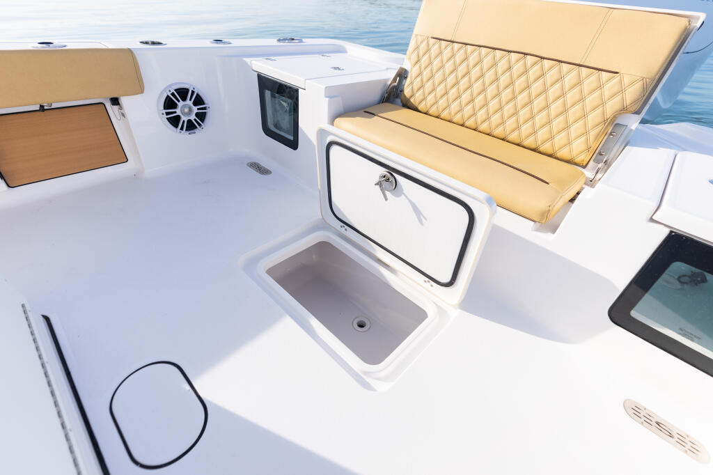 Boat's starboard deck with tan padded seating, in-deck fish box with storage locker, and electronics display