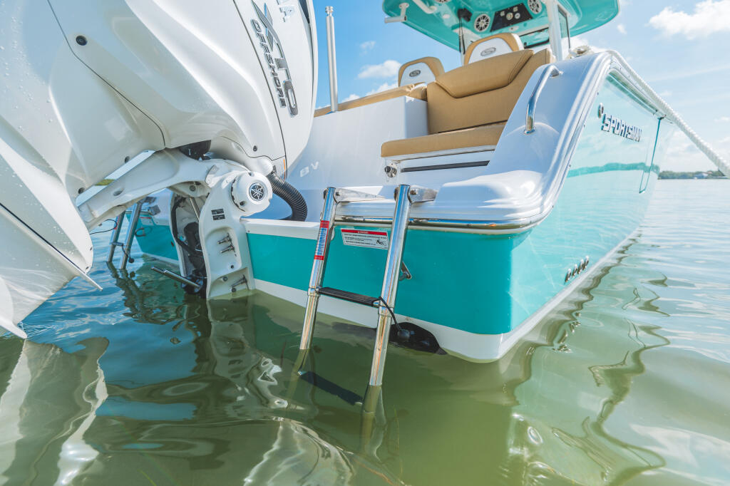 Twin stainless steel boarding ladders on turquoise and white center console boat in shallow water