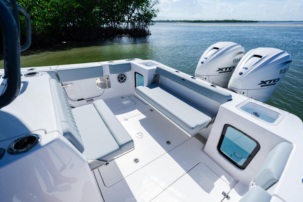 White center console boat with dual outboard engines docked near mangroves in calm tropical waters