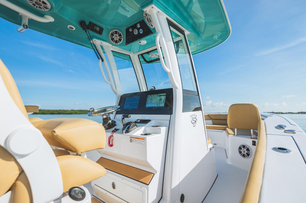 Helm station with dual screens, tan bolstered seating, and hard-top canopy with turquoise interior and white frame