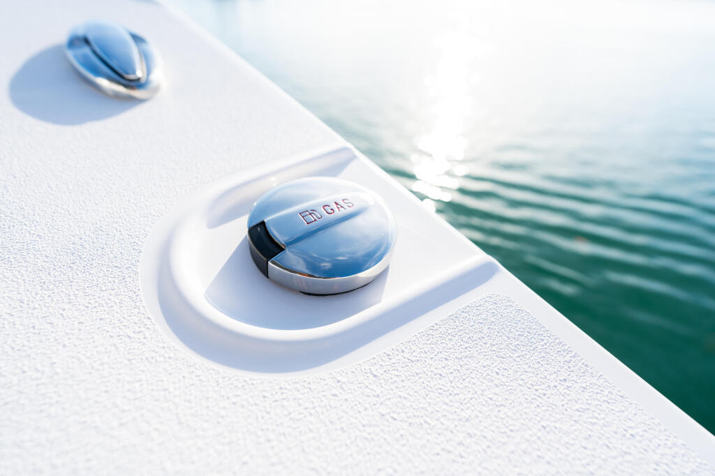 Close-up of boat's white hardtop with polished chrome vents and water beyond