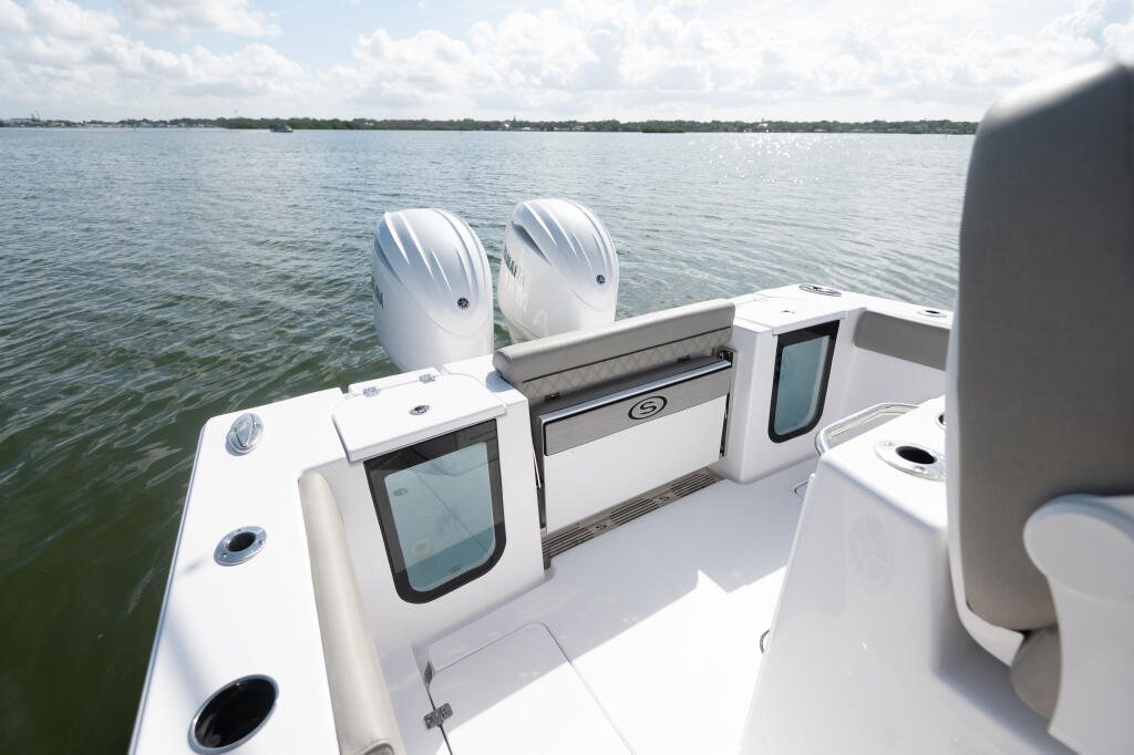 Twin outboard engines and open center console with livewell and storage on calm water