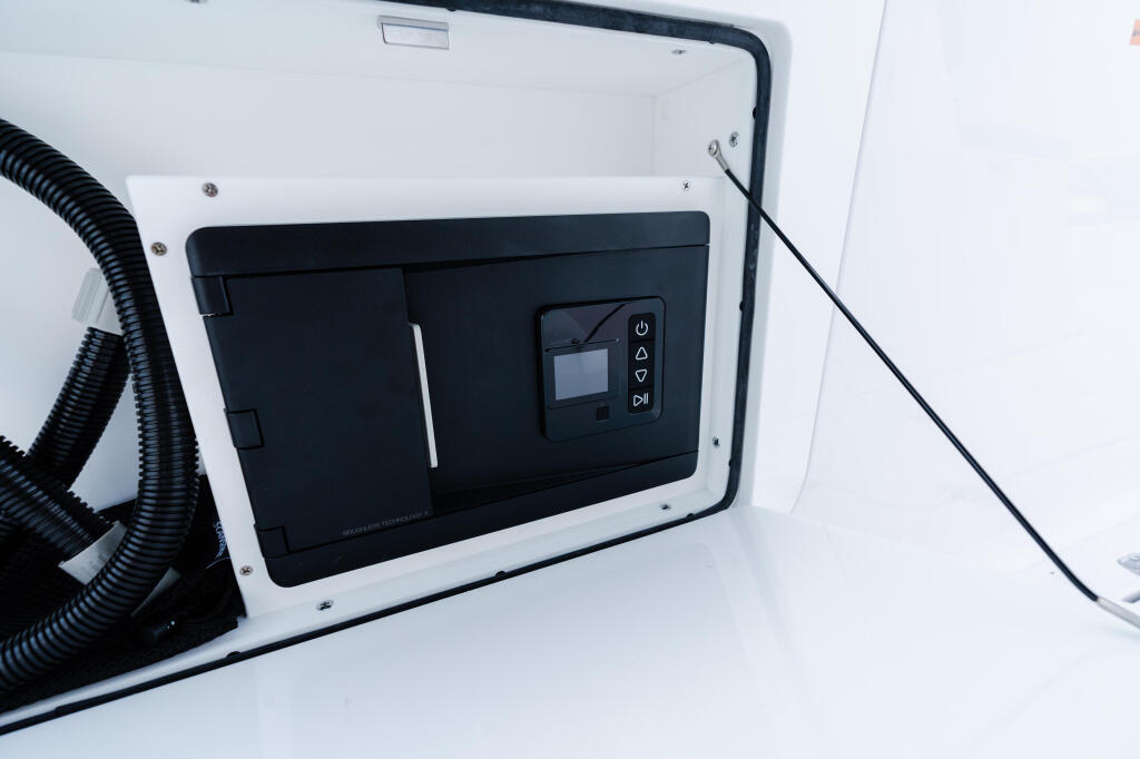 Black and white marine electrical control panel mounted in white fiberglass cabinet with power button and display screen
