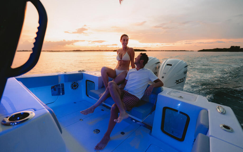 Couple relaxing in a blue center console boat at sunset with calm waters and a Canadian flag visible