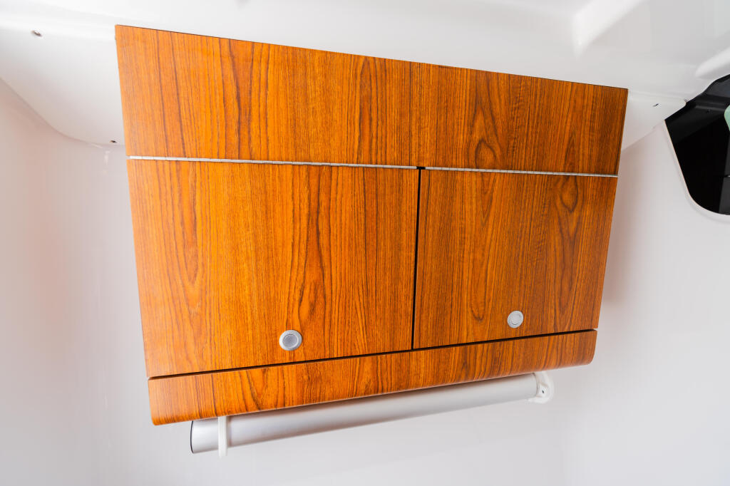 Teak wood cabinetry with multiple storage compartments and chrome handles mounted on white wall