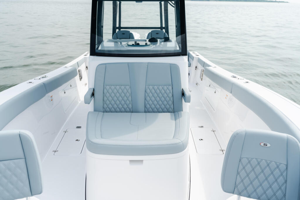 Center console fishing boat with gray quilted seating, white hull, and black hard-top canopy viewed from above