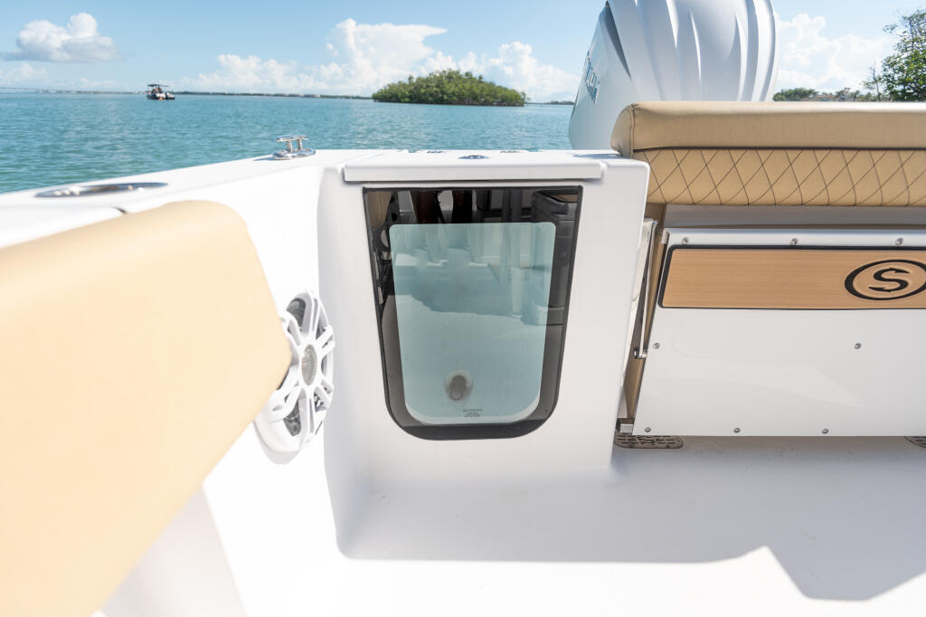 Center console boat with cream-colored seating and white cabin featuring a tinted window overlooking turquoise water and mangrove islands