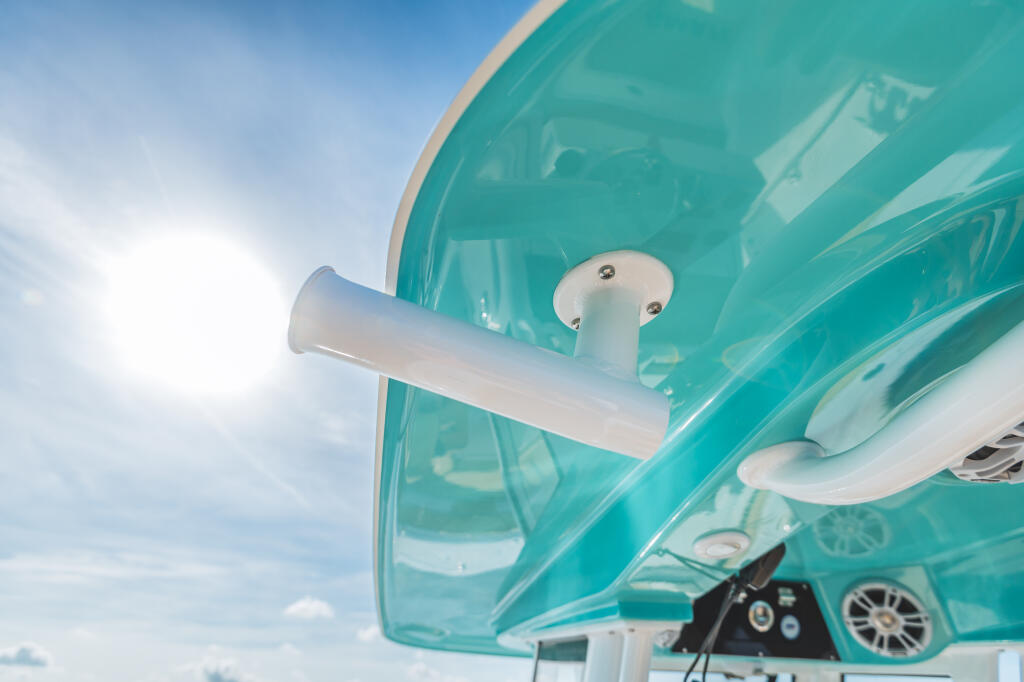 Turquoise hardtop with white rod holders and fishing equipment mounted against blue sky
