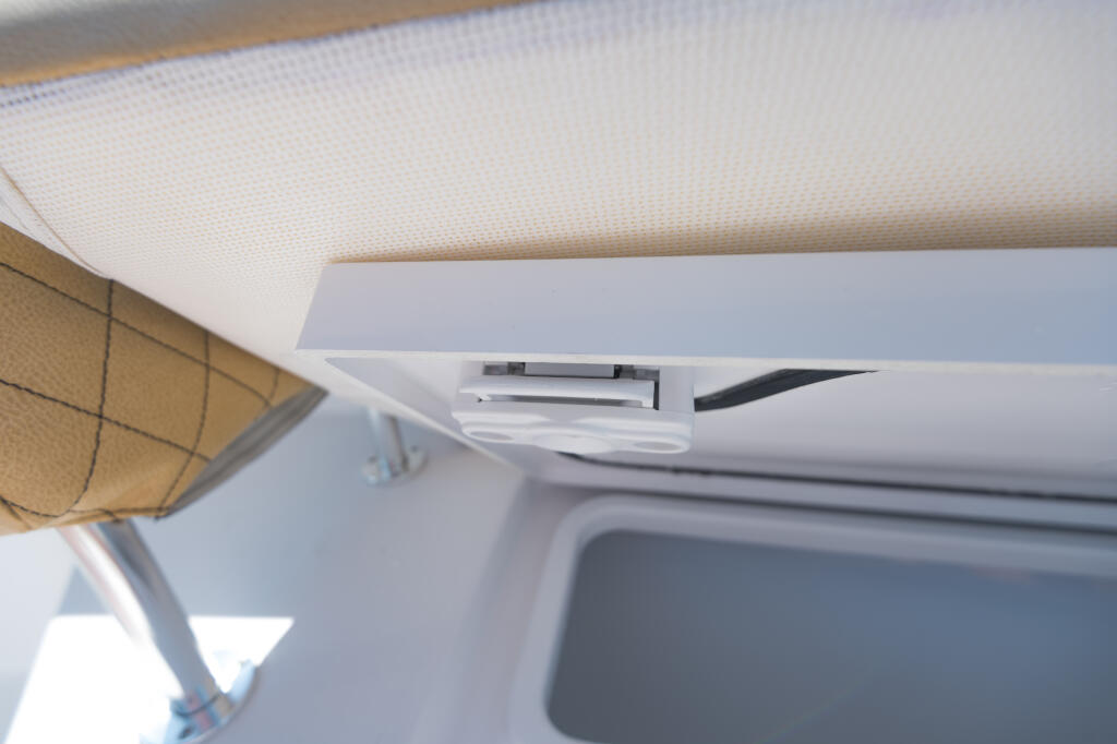 Center console overhead compartment with paddle-style latch mechanism open showing interior storage space