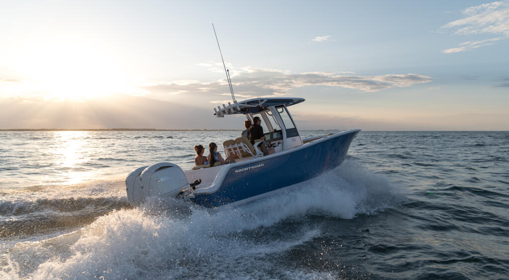 Center console fishing boat with passengers cruising through beach waves at sunset