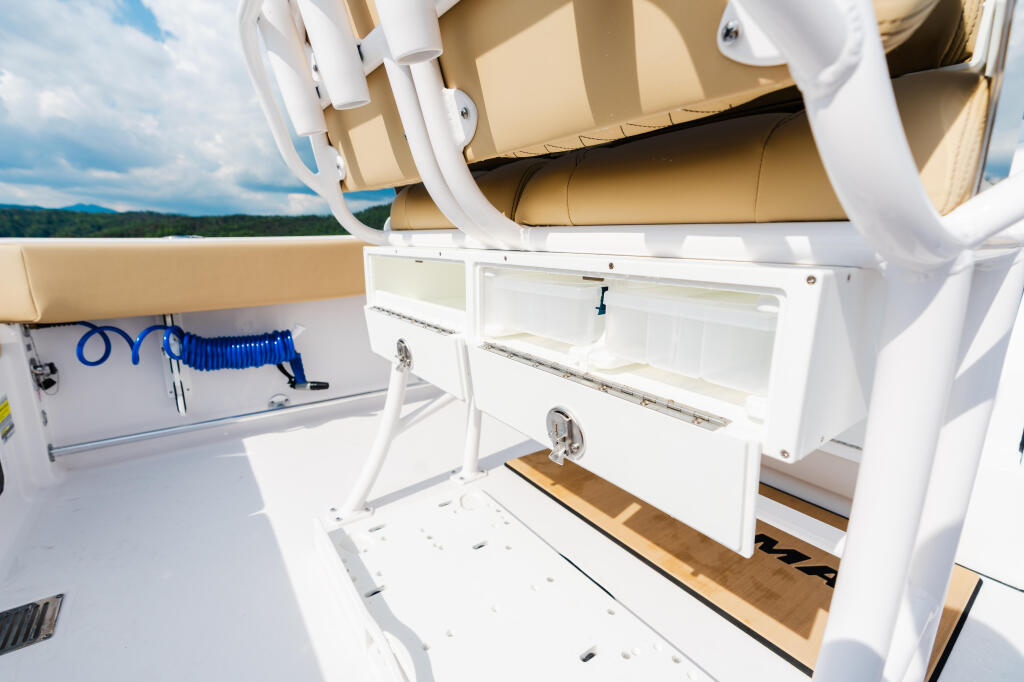 Open storage compartments and equipment on the aft deck of a boat with water view in background