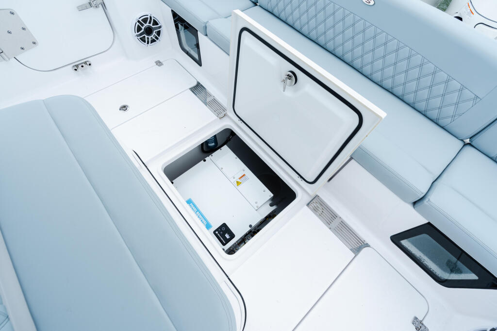 Overhead view of boat deck showing open livewell storage compartment with padded blue seating and electronics panel